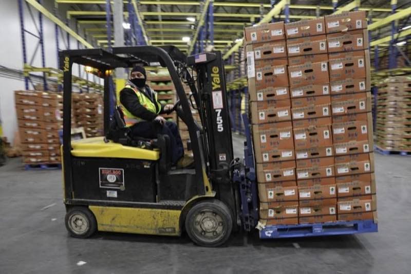 Chariot élévateur déplaçant une palette de produits emballés dans un entrepôt