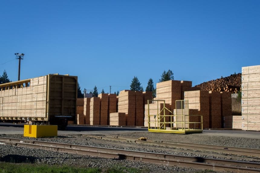 Stacked lumber in a mill yard under a clear sky